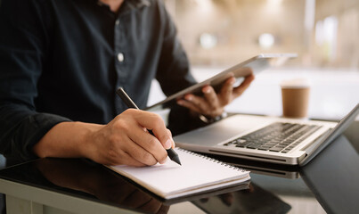 view of young professional businessman writing his idea concepts on notebook while working on his...