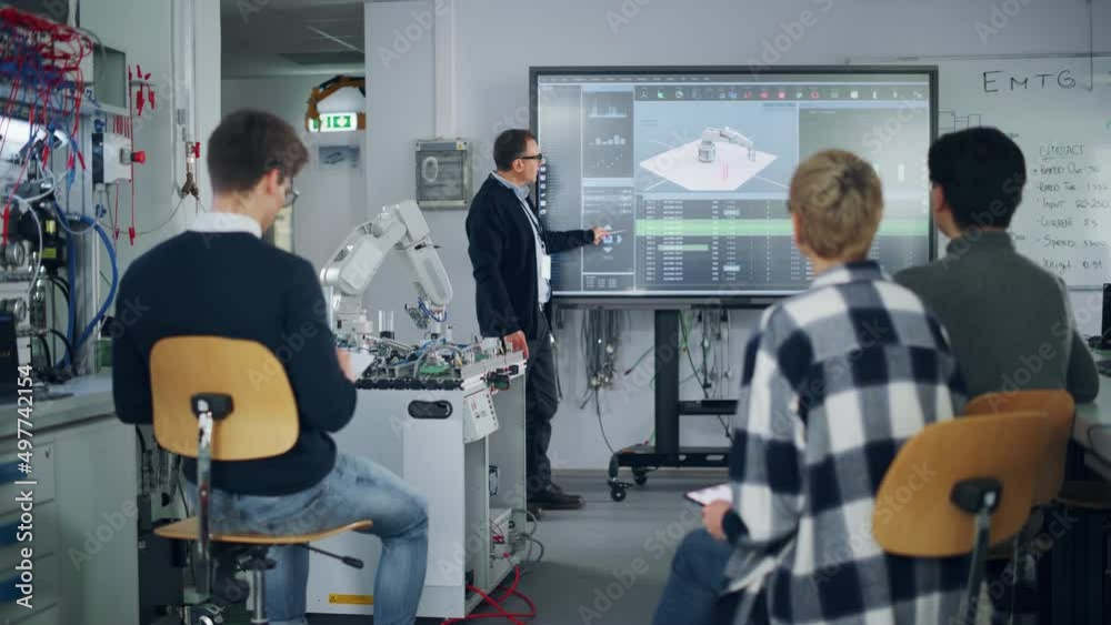 Poster teacher pointing at big screen and holding lesson while robotic arm moving nearby. diverse group of 