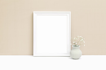 Fototapeta na wymiar Mockup of a white wooden frame with a vase on the table