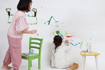 Sisters painting the wall with paints