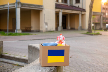 A box with a Ukrainian flag for donating humanitarian aid with things and children's toys for Ukrainian refugees on the street. Stay with Ukraine.