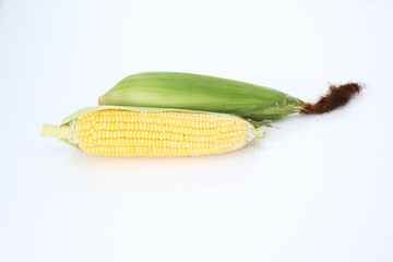 Fresh ripe sweet corn with green leaves, isolated on white background.