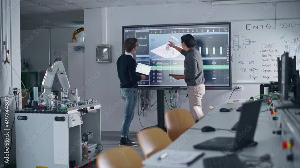 Aufkleber two diverse male students standing near big screen and developing program for motion of robotic arm.