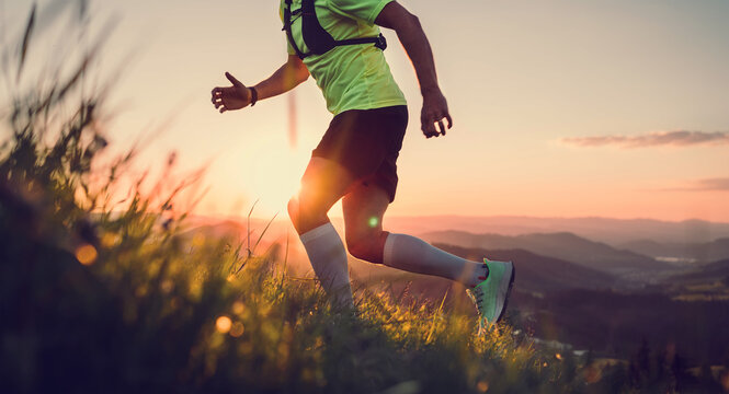 Cropped photo of Middle-aged mountain trail runner man dressed bright t-shirt with a backpack endurance running uphill by picturesque hills at sunset time. Sporty active people concept image.