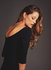 She is elegance personified. Studio shot of a beautiful woman with long locks posing against a grey...