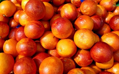 Heap of red blood oranges under the sunlight in the market stall.