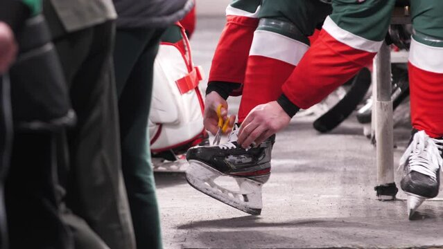 Hockey player cuts laces on skate boot preparing for game at sports stadium close view slow motion. Winter athletic game
