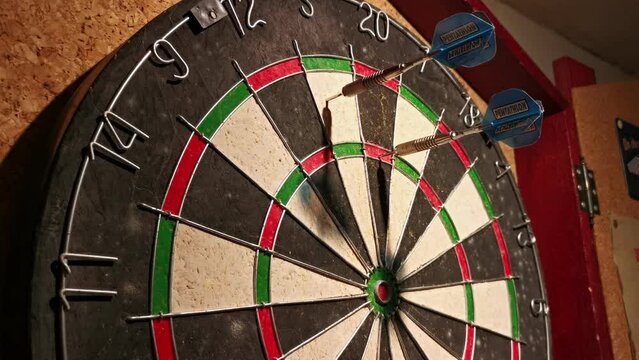 Three dart arrows hitting 85 points on an old basement dart board. Close-up side view