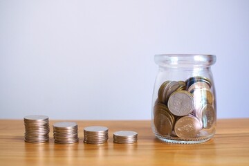 Coins in glass jars with stacks of money step up grow save money, financial business investment ideas.