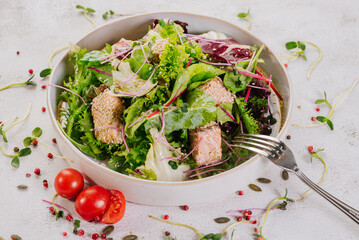 Fish dish with lettuce and sesame seeds on a white background. Diet menu