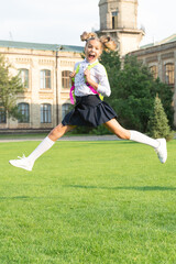 Happy ecstatic girl in uniform back to school jumping for joy, September 1