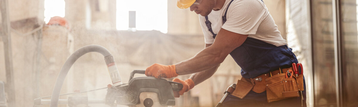 Male Builder Using Wood Cutting Circular Saw Machine In Workshop