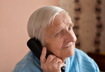 Fototapeta premium close-up of a 90-year-old elderly retired woman who is talking smiling on the phone.