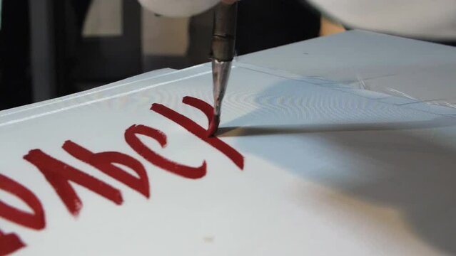 Supporter writes word with red color to draw placard for hockey match at table closeup slow motion. Artist at work