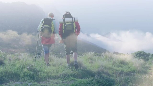 Composite video of clouds against caucasian couple hiking on the mountains