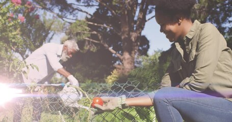 Spot of light against african american father and daughter gardening together in the garden
