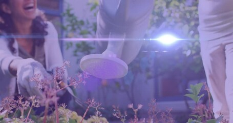 Spot of light moving against mid section of a caucasian girl watering plants in the garden