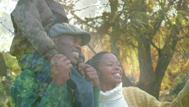 Animation of leaves over happy african american couple with child