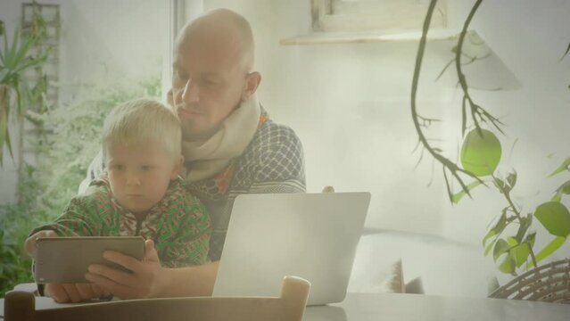 Animation of light spots over happy caucasian father using tablet with child