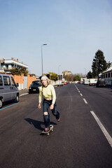 Young diverse rebel alternative queer woman skating riding longboard outdoor