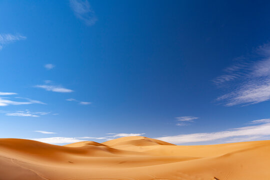 Paesaggio desertico con dune di sabbia alte e sfondo cielo blu