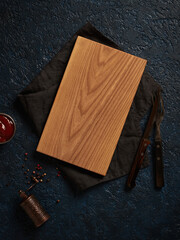 Top view of a wooden cutting board and kitchen utensils