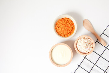 Natural ingredients for homemade face mask, top view of yoghurt, oat and turmeric on white background, beauty skincare product concept, flat lay
