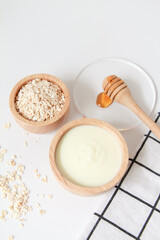 Natural ingredients for homemade face mask, top view of yoghurt, oat and honey on white background, beauty skincare product concept, flat lay