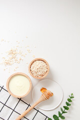 Natural ingredients for homemade face mask, top view of yoghurt, oat and honey on white background, beauty skincare product concept, flat lay