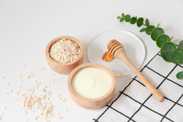 Natural ingredients for homemade face mask, top view of yoghurt, oat and honey on white background, beauty skincare product concept, flat lay