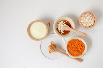 Natural ingredients for homemade face mask, top view of yoghurt, turmeric, oat and honey on white background, beauty skincare product concept, flat lay