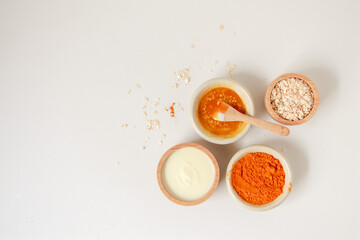 Natural ingredients for homemade face mask, top view of yoghurt, turmeric, oat and honey on white background, beauty skincare product concept, flat lay
