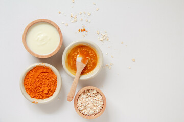 Natural ingredients for homemade face mask, top view of yoghurt, turmeric, oat and honey on white background, beauty skincare product concept, flat lay