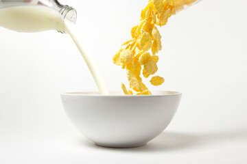 Corn flakes and milk are poured into a plate. Cooking a delicious and healthy breakfast. Healthy diet