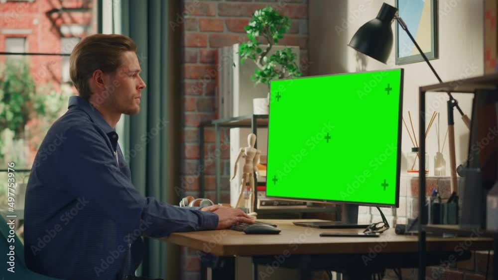 Poster young handsome man working from home on desktop computer with green screen mock up display. male che