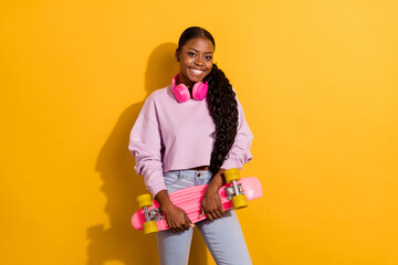 Photo of friendly positive attractive person hold skateboard enjoy free time isolated on yellow...