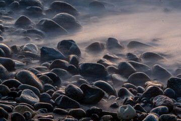 Pietre in una spiaggia in riva al mare all'ora del tramonto 