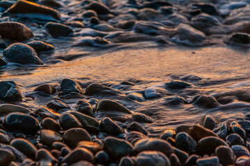 Pietre in una spiaggia in riva al mare all'ora del tramonto 