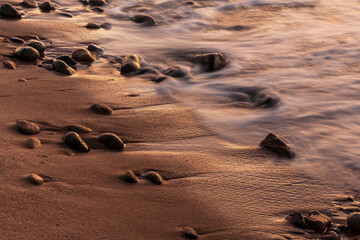 Fototapeta na wymiar riva del mare con le onde che si infrangono sui ciotoli di pietra 