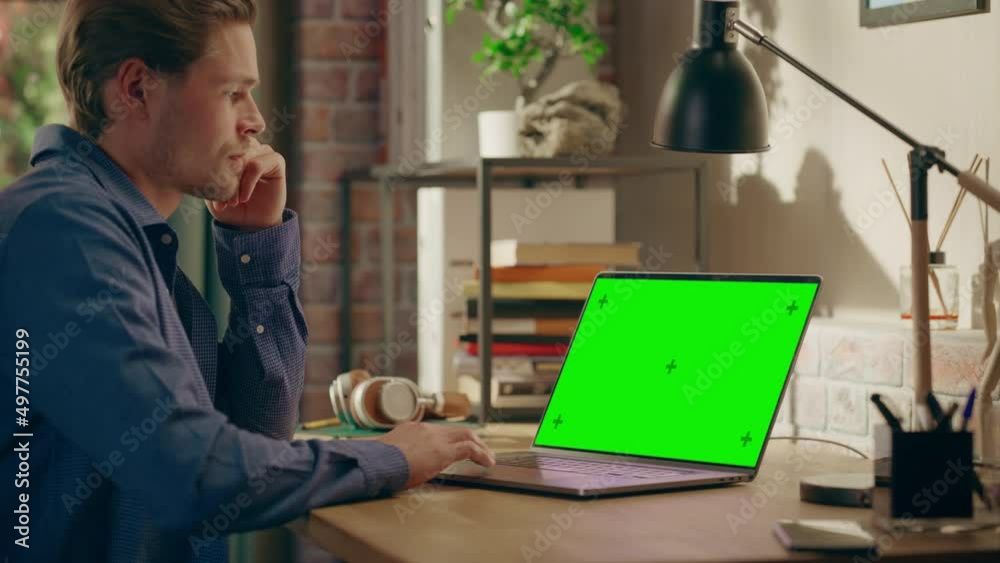 Poster young handsome man working from home on laptop computer with green screen mock up display. creative 