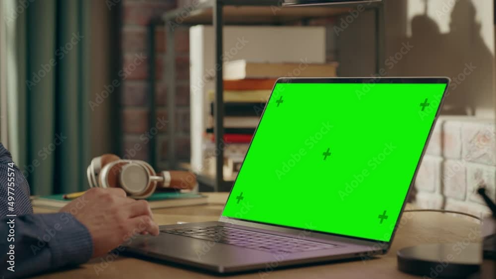 Poster close up on male hands working from home on laptop computer with green screen display, person using 