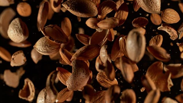 Super Slow Motion Shot of Flying Whole Almonds and Nut Shells Towards Camera on Black at 1000fps.