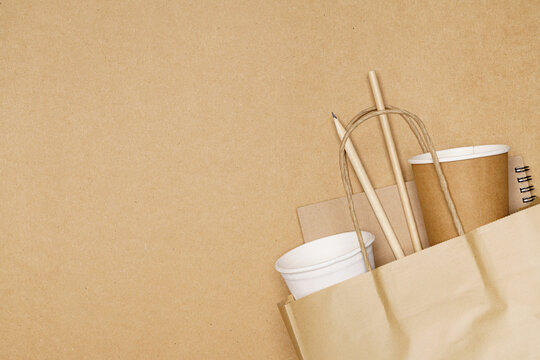 Eco friendly concept, notebook pencil and paper cup with straws in paper bag on wooden background
