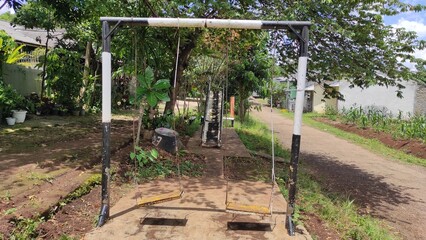 A rusty and tilted swing bench in a park in the Cikancung area, Indonesia