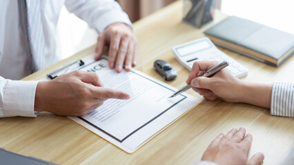 Insurance concept the male dealer suggesting his customer to sign the contract of car purchasing