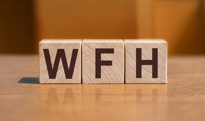 Wooden blocks with letters WFH - Work From Home - on orange background. New business concept.