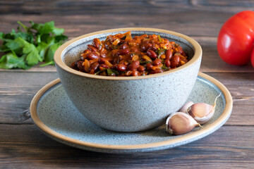 Lobio made of stewed red beans in bowl on wooden background