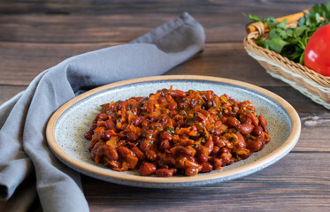 Lobio made of stewed red beans on wooden background with gray textiles