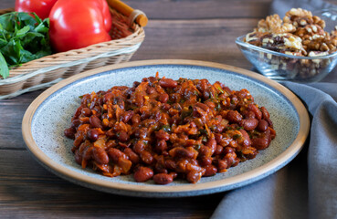 Lobio made of red beans on wooden background with gray textiles, close-up