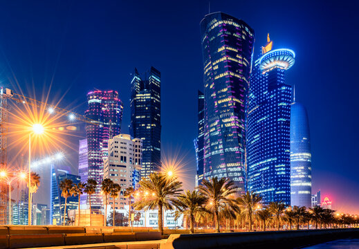 Night view in the city center of Doha, Qatar with many modern luxury buildings and skyscrapers illuminated with numerous lights.